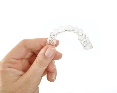 A person holding an Invisalign tray