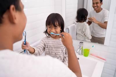 A father and daughter brushing their teeth