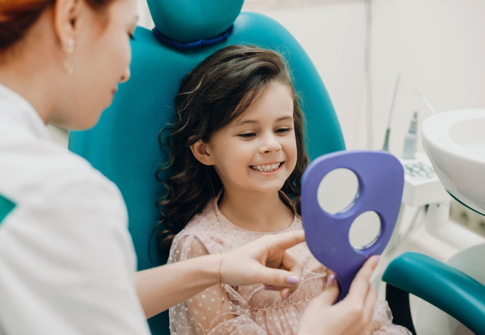 A smiling child looking in the mirror at the dentist