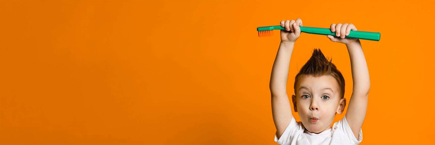 A boy holding a large toothbrush