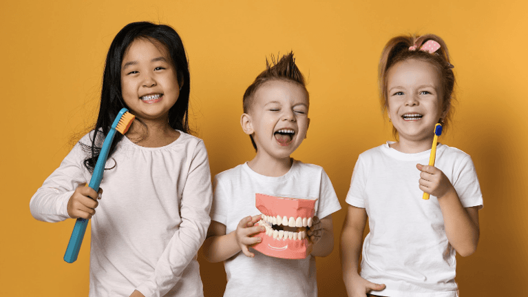 Three smiling children with large toothbrushes