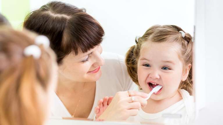 A mother brushing her daughter's teeth