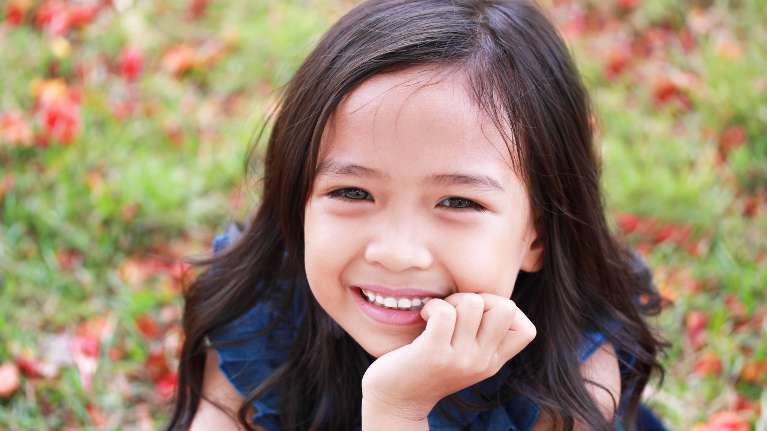 A smiling girl sitting in leaves