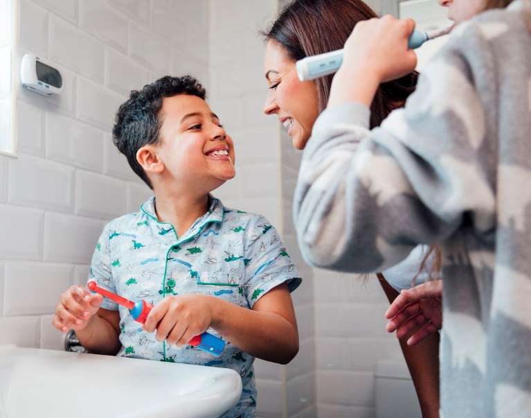 A mother helping her two children brush their teeth