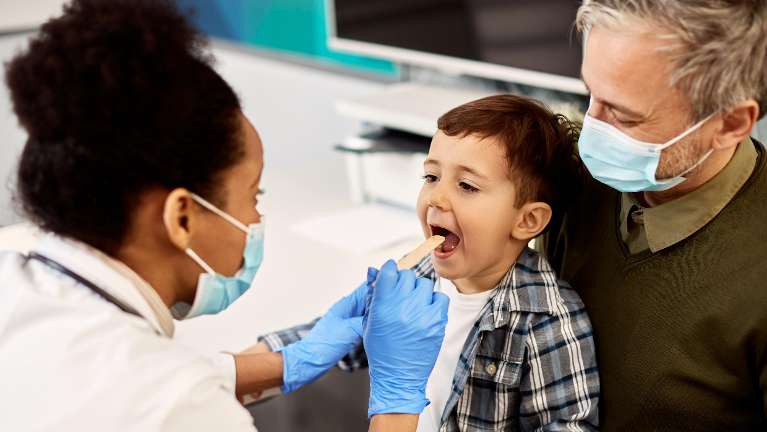 A dentist using a tongue depressor on a child